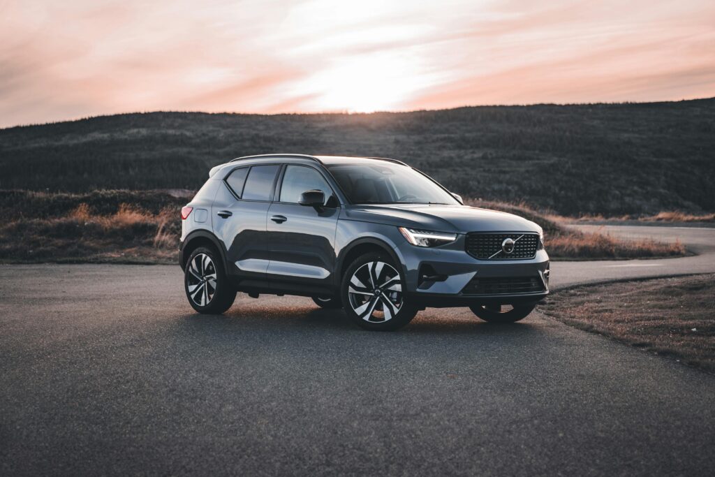 pexels-photo-20695244-20695244 A Volvo SUV parked on a scenic road at sunrise, surrounded by hills.